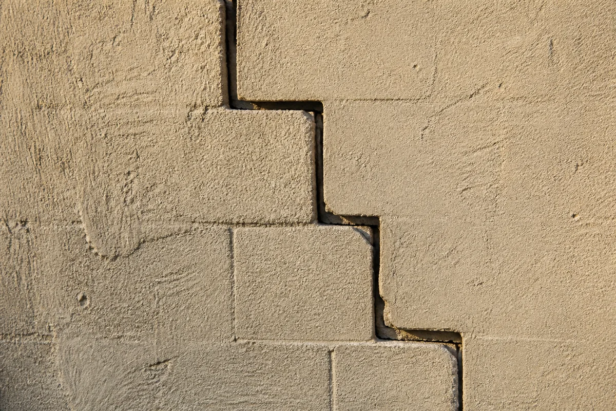 Fissure en escalier sur une façade de maison, signe de mouvement de sol