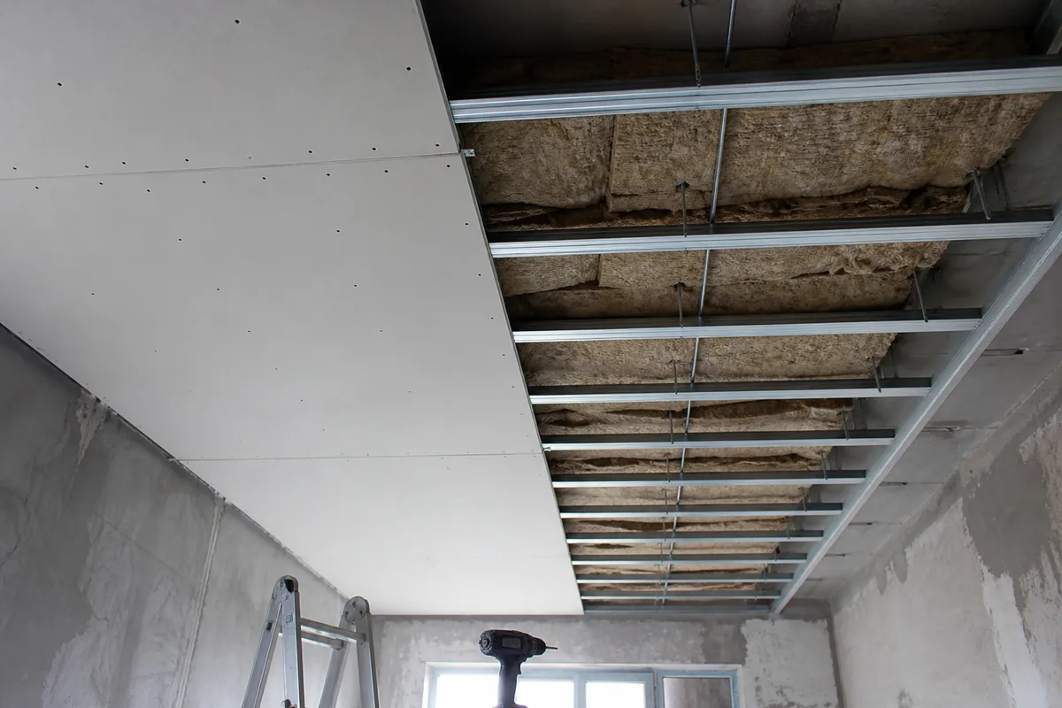 Plafond suspendu en cours de pose sur suspentes, plaques de parement partiellement vissées